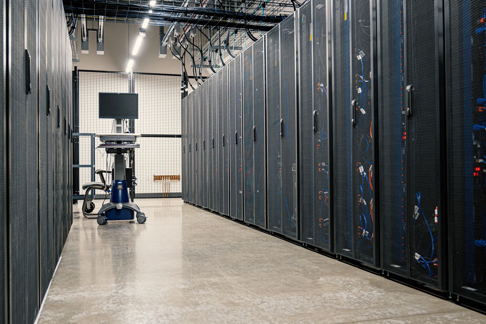 Pasillo de un centro de datos con hileras de racks y cableado de red